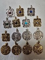 Group shot of all fourteen pendants showing variety of shapes, finishes and motifs