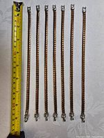 Eight bracelets lined up beside measuring tape