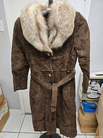 Full view of brown suede coat hanging on stand