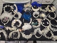 Full table view of approximately 25 bridal hair accessories on black cloth