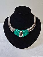 Front view of silver-tone collar choker with green ridged centerpiece and silver oval accent