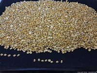 Large pile of gold beads on black surface
