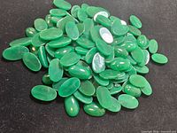 Pile of chrysoprase cabochons on black background
