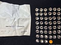 Paper packet with printed specs beside array of rhinestones