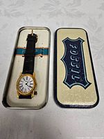 Watch in open Fossil tin alongside lid