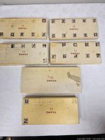 Six Omega cream cardboard boxes with letters/numbers on lids