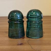 Front view of both Brookfield glass insulators on wooden surface