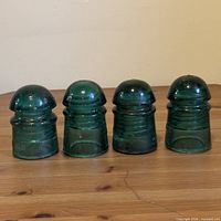 Four teal glass insulators in a row on wooden surface