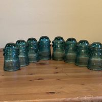 All eight aqua Hemingray No. 9 glass insulators lined on table