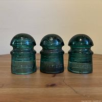 Front view of three Brookfield aqua glass insulators