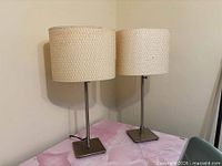 Two brushed metal table lamps on table