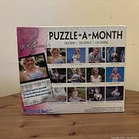 Front of factory-sealed Puzzle-A-Month box showing Marilyn Monroe images and piece count