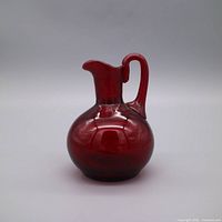 Front view of ruby red pressed glass pitcher showing handle and spout