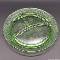 Front view of green divided dinner plate showing etched floral border and dividers