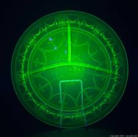 Plate glowing under UV light showing Cameo pattern and uranium fluorescence