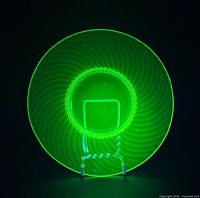 Plate glowing bright green under UV light, showing spiral ribbed design