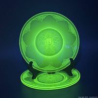 Plate glowing bright green under UV light on stand, additional plate beneath