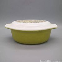 Side view of avocado green Pyrex casserole with white olive-pattern lid