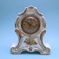 Front view of white ceramic mantel clock with gold trim and floral decal