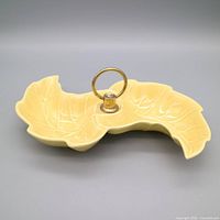Top view showing full double leaf form, yellow glaze, brass ring handle