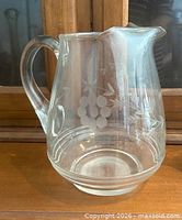 Front view of clear glass pitcher showing etched floral design and handle