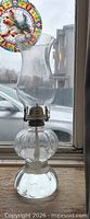 Full view of glass hurricane lamp showing chimney, burner, font and base