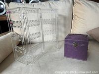 Clear plastic folding earring divider next to closed purple travel jewelry box