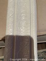 Close view of embossed pattern on trim showing floral scroll design and dual-bead profile