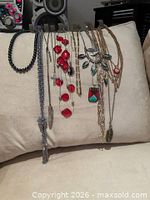 Group shot of all nine necklaces hanging on cushion