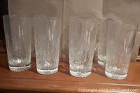 Front view of six tall pinwheel cut glass tumblers
