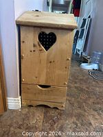 Front view of closed wooden bin showing heart cutout and overall appearance