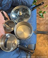 Overall view of saucepan, smaller pot, steamer insert, egg poacher pan with lid