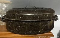 Side view of closed oval black speckled roasting pan
