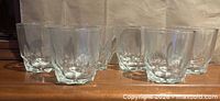 Seven clear rock glasses on wooden surface