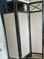 Full front view of three-panel divider showing black frame and beige fabric