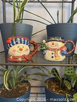 Both ceramic snowman mugs on shelf showing overall condition