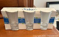 Front view of sealed three-piece shot glass set in original carton