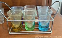 front view of six colored shot glasses seated in metal carrier