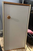 Front view of white cabinet with closed door and wooden knob