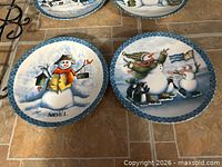 Two plates showing Noel snowman and skating snowmen with penguins