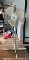 Full view of beige pedestal fan showing cage, blades, pole and base