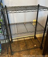 front view of three-tier metal plant stand showing shelves and wheels