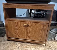 Front view of TV stand showing closed drop-down door and casters