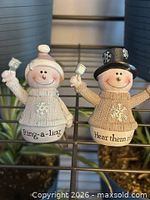 Front view of both snowman figurines showing text on bases