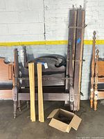 Two twin bed frames components leaning against wall with slats and hardware box