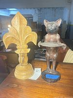 Cast iron cat statue and wooden finial side by side