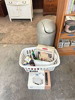 Lot overview showing laundry basket with boxed items, grill cover box in front