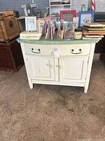 Front view of cream cabinet with distressed green top showing drawer and doors