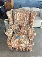 Front view of floral tapestry wingback armchair with two matching pillows