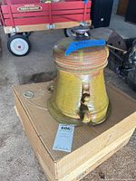 Overall view of glazed ceramic hanging planter with wire hanger on box